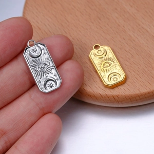 Detailed relief of sun and moon icons on rectangular steel charms in gold and silver