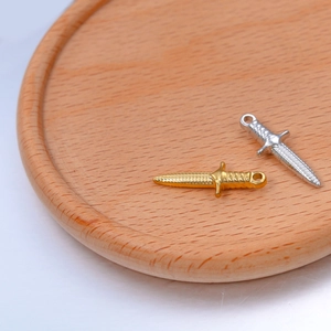 Macro detail of gold and silver sword pendants with textured blades on wood tray
