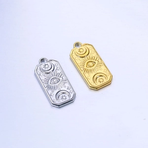 Detail view of gold and silver rectangle charms with celestial sun and evil eye embossing