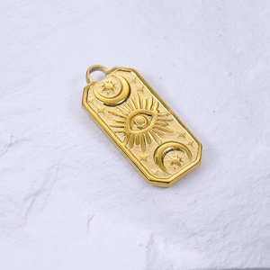 Macro detail of gold rectangle pendant with sun eye and moon embossed astrology symbols