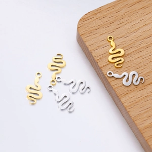 Detailed view of polished snake pendants in gold and silver on a wooden display board