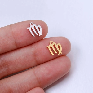 Close-up of gold and silver Virgo zodiac pendants shown on fingertips for size scale