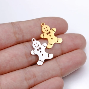 Detail of gold and silver gingerbread man pendants held by hand for scale and texture