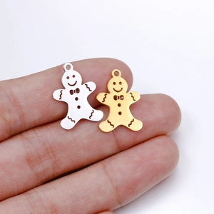 Close-up of gold and silver gingerbread man pendants held to show the small scale and mirror finish