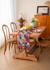 Detail of bohemian jacquard table runner with tropical patterns and dark red tassels