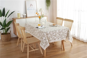Detail of floral tablecloth with white lace border on a wooden dining table