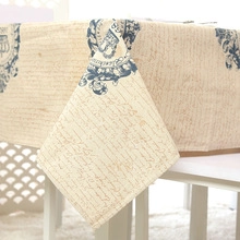 Close-up of vintage beige tablecloth featuring navy crests and script lettering details