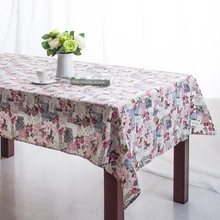 Detail of floral and newspaper print tablecloth with lace edge on a wooden table