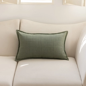 Detailed texture of dark green jacquard plaid cushion cover on a soft fabric sofa