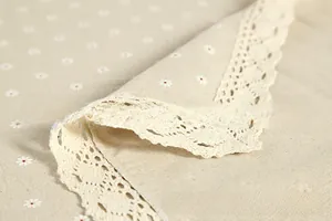 Detail of daisy print linen tablecloth with delicate crochet lace edge in cream