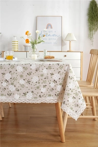 Detailed close-up of beige tablecloth with dandelion print and wide lace border edge