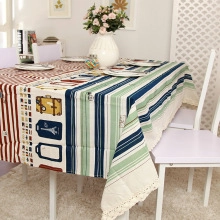 Detail of travel-themed tablecloth with olive branch lace trim and colorful stripes