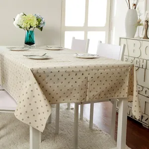 Detailed view of beige floral linen tablecloth with brown daisy patterns on a dining table