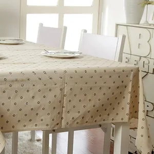 Close-up of beige linen tablecloth with small daisy print and neat edge stitching
