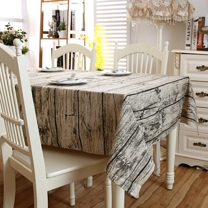 Detailed view of rustic wood grain patterned tablecloth with lace edge in a cozy home setting