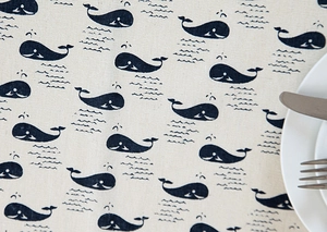 Close-up of ocean whale pattern linen tablecloth with decorative plate and cutlery