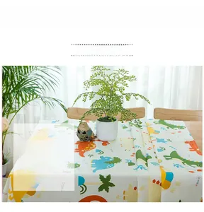 Detail of thick cotton tablecloth featuring colorful cartoon dinosaurs on a wooden table