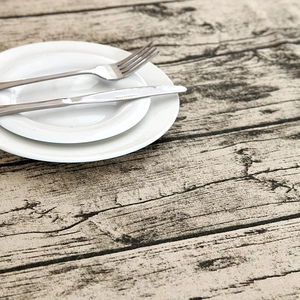 Detail of faux bark wood grain tablecloth with white ceramic plates and cutlery