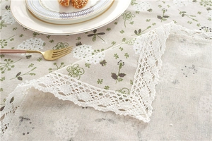 Detailed macro view of cream table cloth with floral print and white lace border