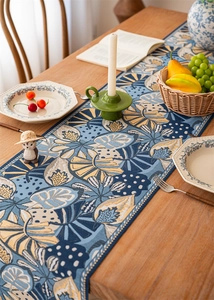 Detail of jacquard table runner with tropical leaf patterns on a wooden dining table