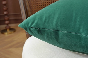 Detail of invisible zipper closure on dark green velvet cushion cover with soft texture