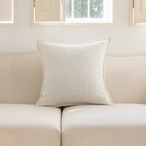 Close-up of ivory checkered throw pillow with textured weave on a minimalist sofa