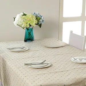 Detail of beige floral linen tablecloth with small daisy print on a rectangular dining table