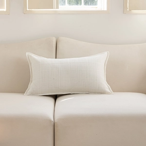 Close-up of cream textured jacquard weave and neat stitching on polyester cushion cover