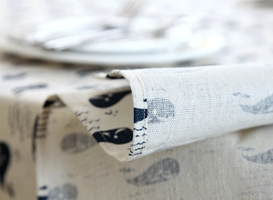 Macro detail of whale print linen tablecloth showing hemmed edges and woven fabric texture