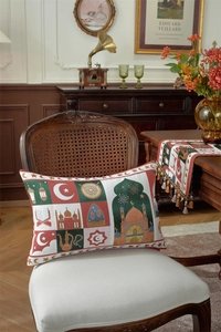 Close-up of a festive lumbar pillow with moon and star embroidery on a vintage chair