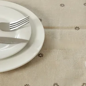 Detailed view of linen texture tablecloth featuring small brown daisy floral patterns