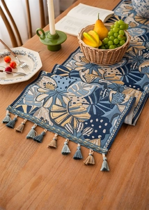 Detailed close-up of jacquard floral table runner with elegant blue and yellow tassels