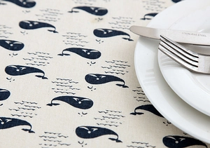 Close-up of linen fabric texture with blue whale print and lace border detail