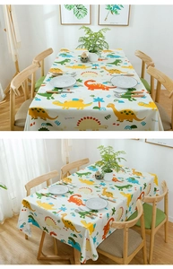 Detail view of cotton tablecloth with colorful cartoon dinosaur patterns and tropical plants