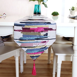 Detailed view of abstract colorful striped table runner with magenta silk tassels