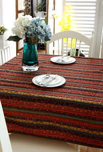 Detail of bohemian gold-striped linen tablecloth with lace edges and colorful patterns