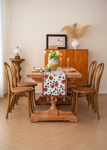 Detail of tropical jacquard table runner with red tomato pattern and fringe tassels