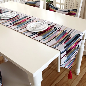 Close-up of colorful oil painting texture fabric on table runner with red tassels