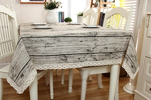 Detailed view of rustic wood grain pattern tablecloth with white lace floral trim edge