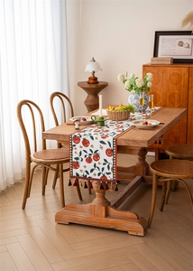 Macro detail of retro floral table runner with red tomato pattern and tassel fringe