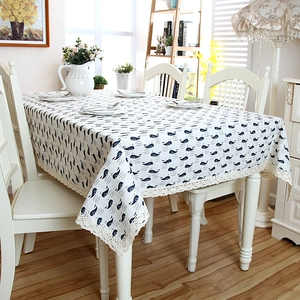Modern linen tablecloth with blue whale print and crochet lace edges on a white dining table