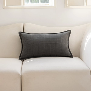 Detail shot of a dark grey rectangular cushion cover featuring a woven jacquard grid texture
