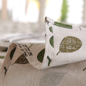 Close-up of green leaf pattern on cotton linen tablecloth with neat hemmed edges