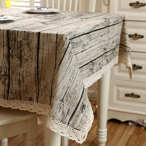Detail of faux wood grain tablecloth with white crochet lace trim in rustic style