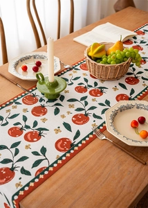 Close-up of jacquard table runner with orange fruit motifs and rustic fabric texture