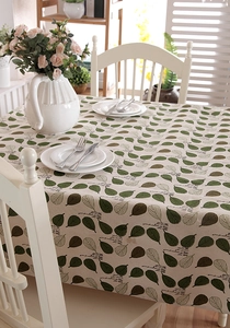 Close-up of rectangular beige cotton linen tablecloth featuring green leaf patterns