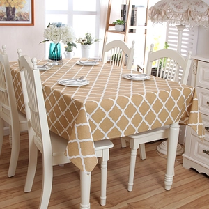 Detail of yellow geometric trellis tablecloth with lace edges on a wooden dining table