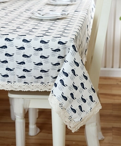 Detailed view of blue whale patterns and elegant wide lace border on linen tablecloth
