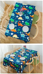 Macro view of thick cotton fabric with cute cartoon dinosaur patterns on navy tablecloth