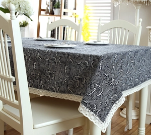 Detail of navy blue wave pattern tablecloth with white lace edges on wooden table